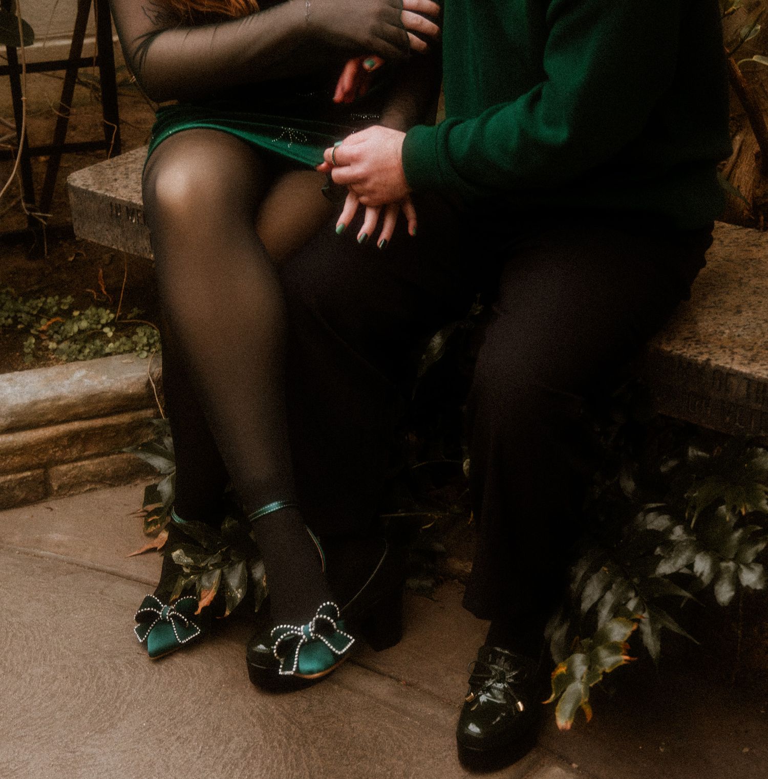 Close-up shot of a couple sitting together on stone steps, focusing on their formal attire.