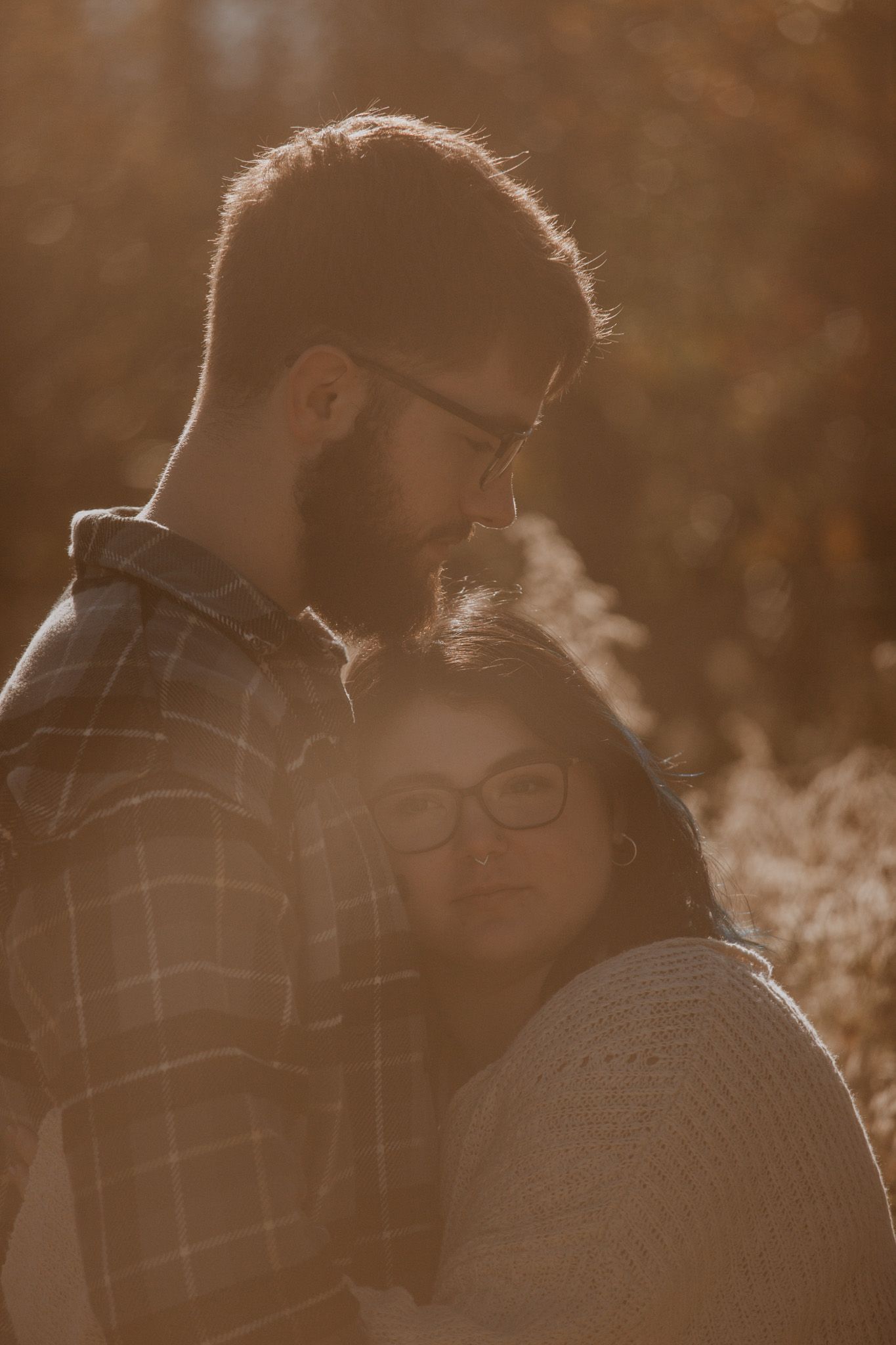 Silhouetted couple in warm sunlight sharing an intimate moment outdoors.