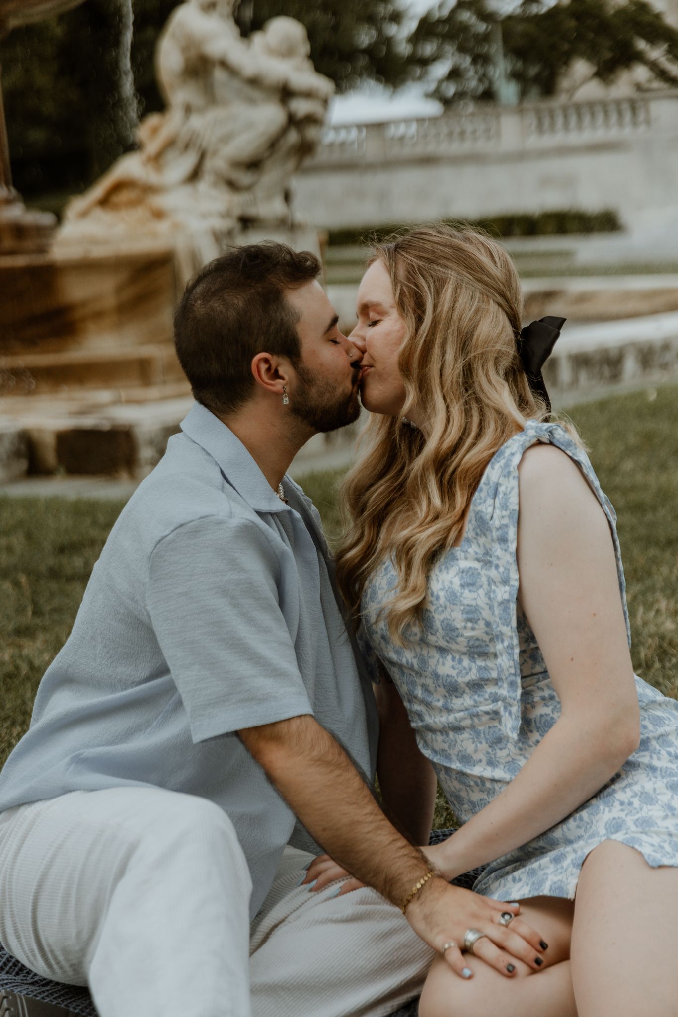 A couple shares an intimate moment during their engagement photo session in a park.