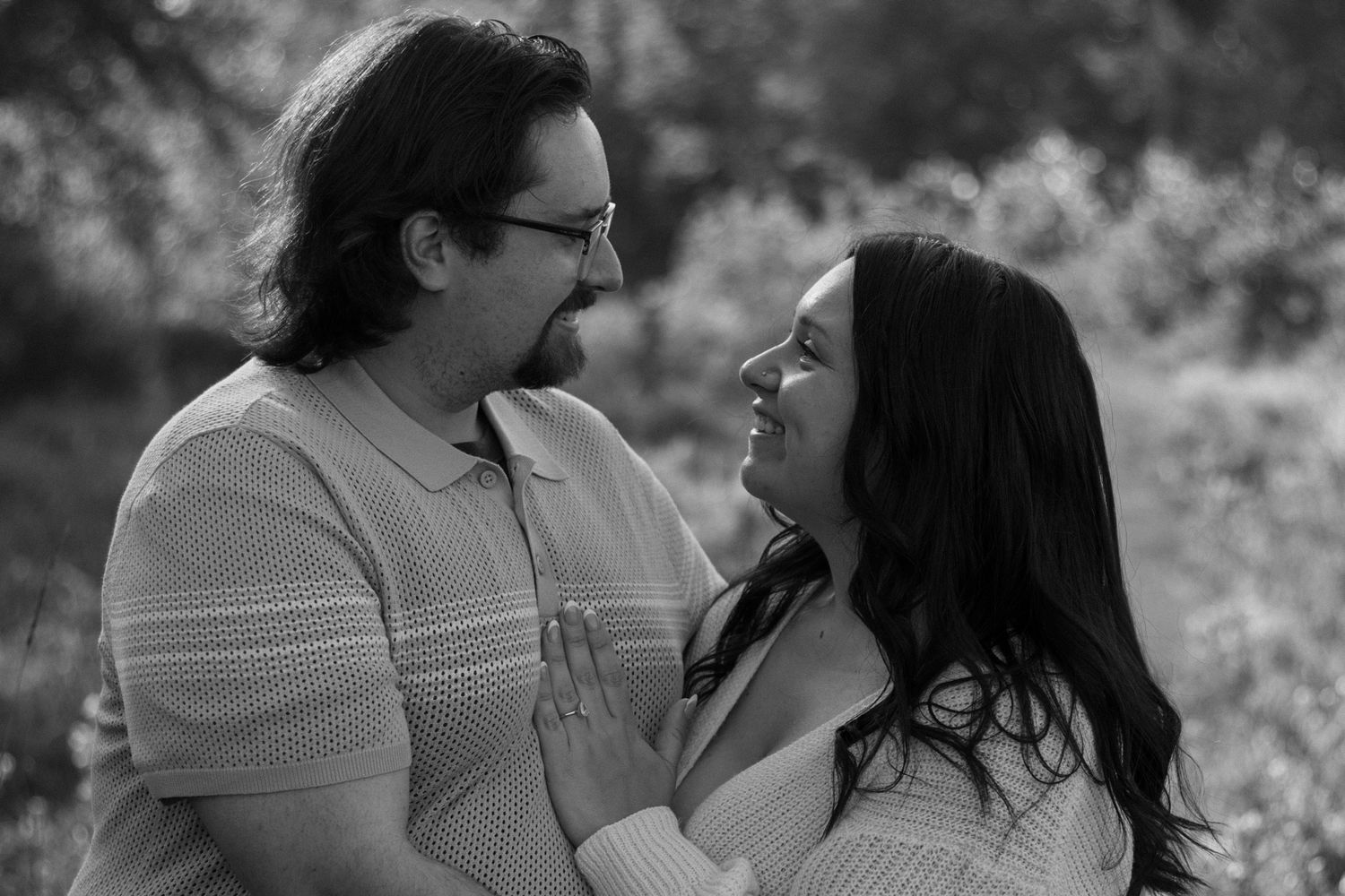 A couple shares an intimate black and white moment outdoors.