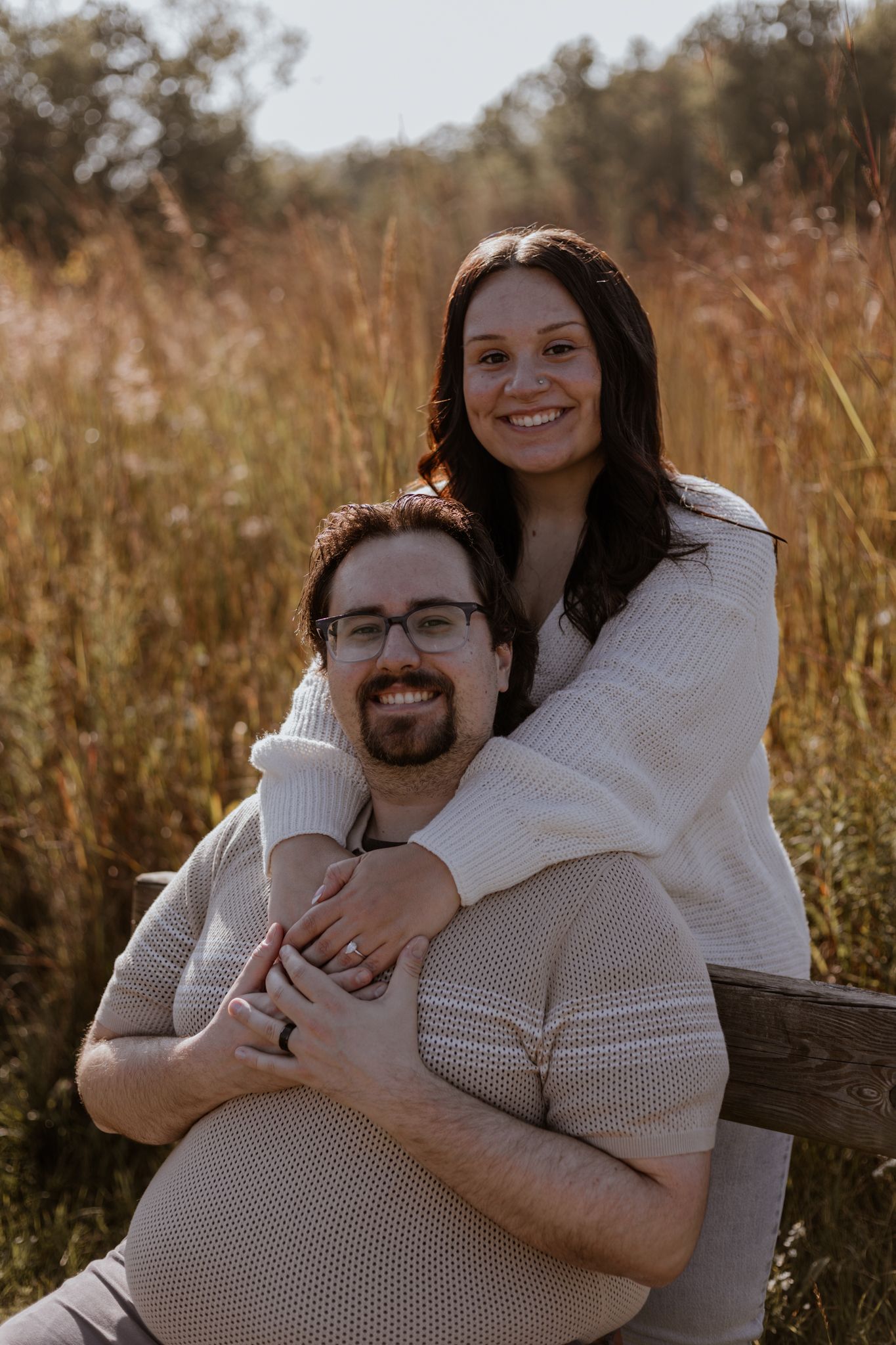 A couple in matching white sweaters shares a tender moment outdoors.