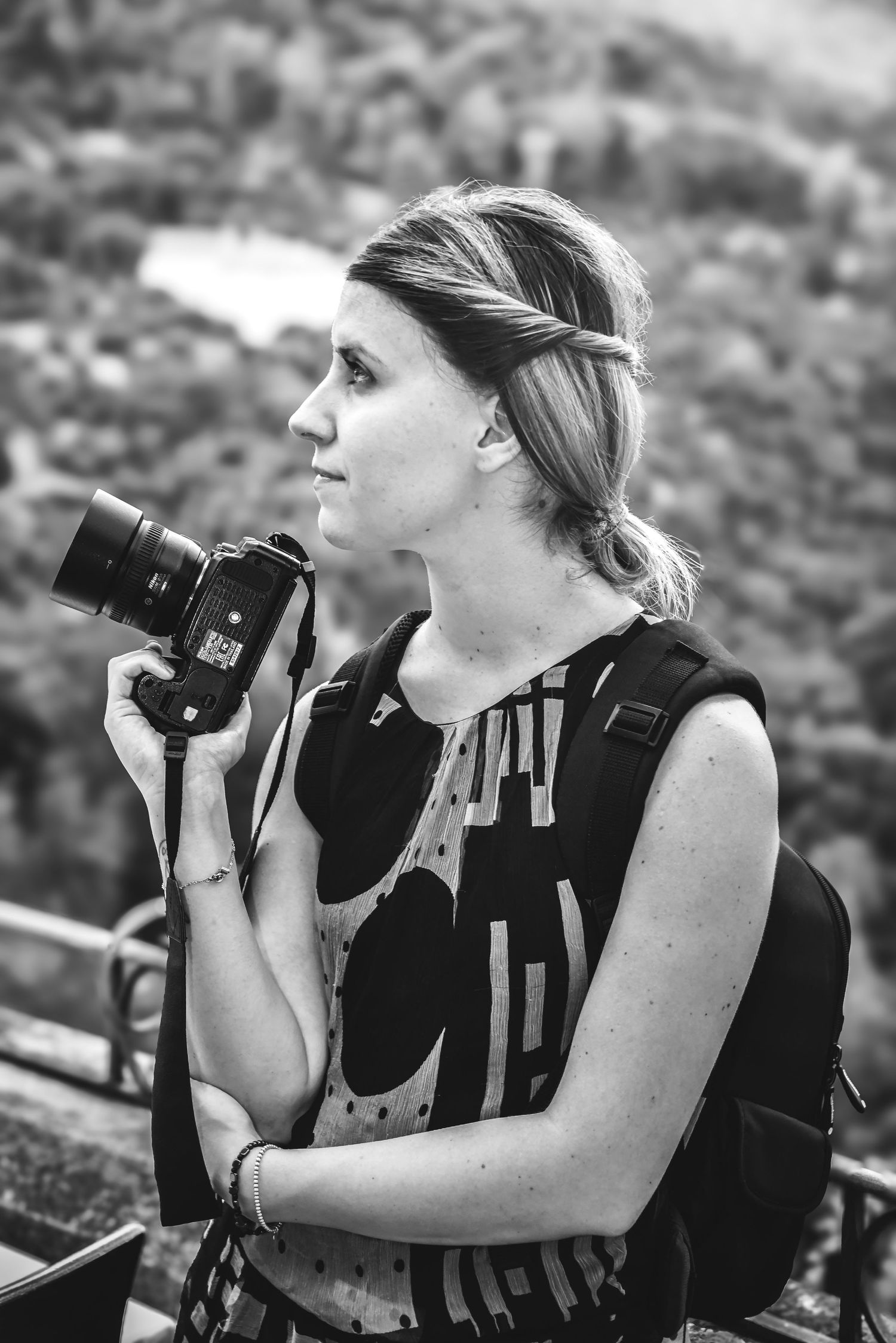 A photographer with braided hair holds a camera while looking into the distance.