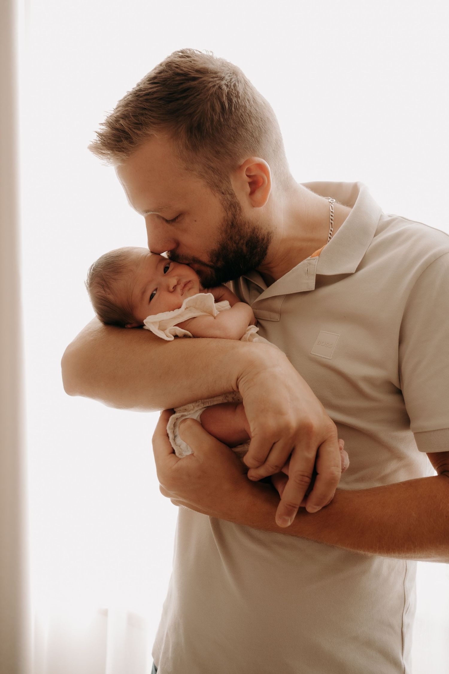 A tender moment between parent and newborn baby captured in soft natural light.