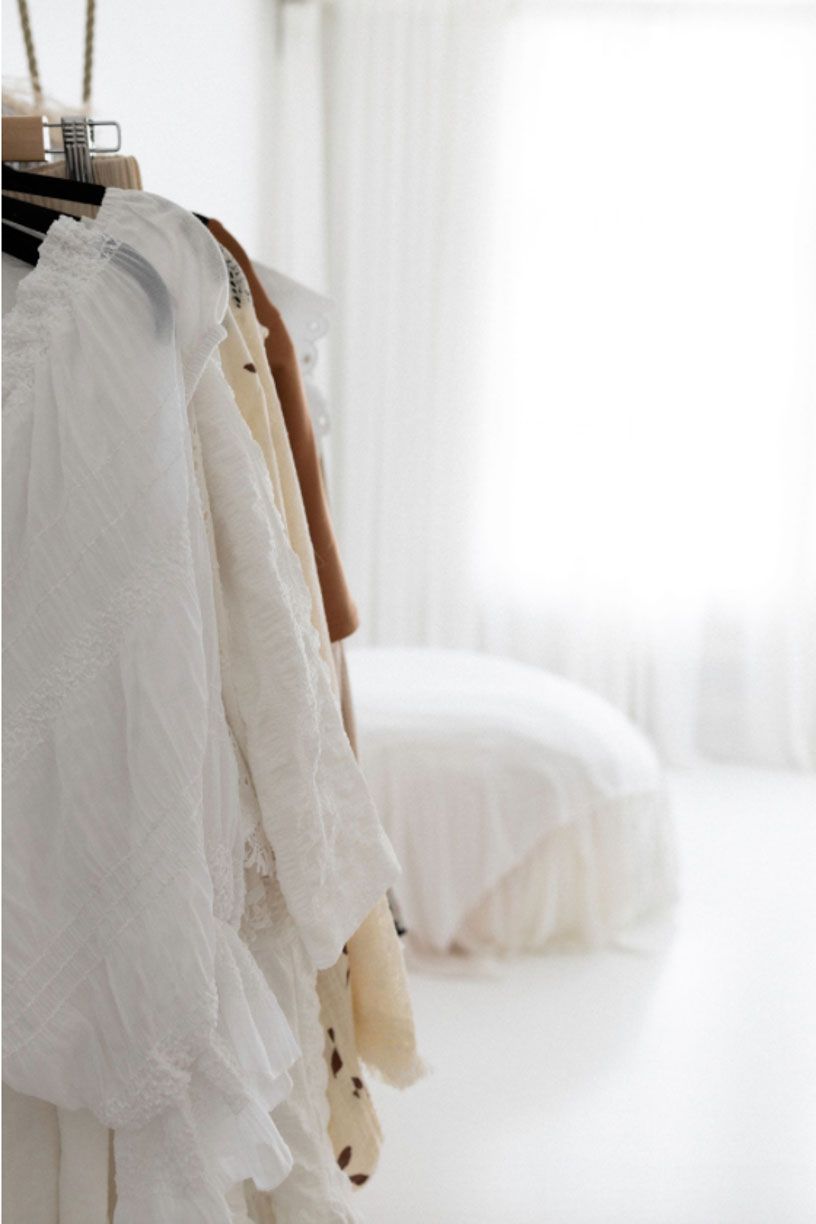 Delicate white lace fabric with intricate patterns hangs elegantly against a bright, airy background.
