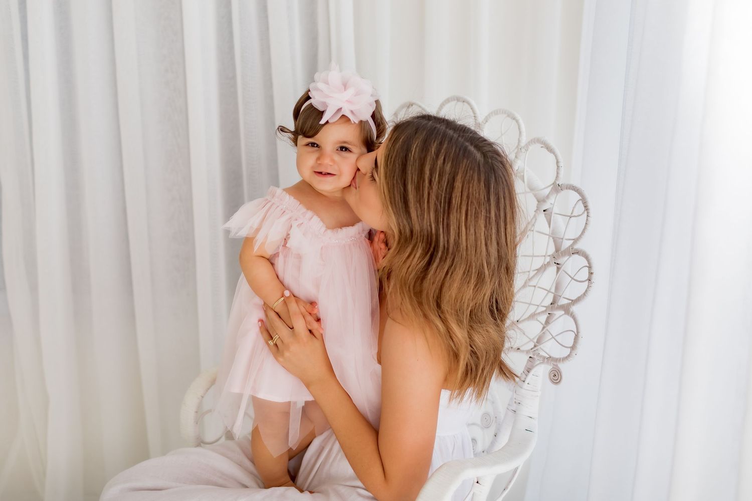 A heartwarming moment captured between two people in matching pink outfits on a white chair.