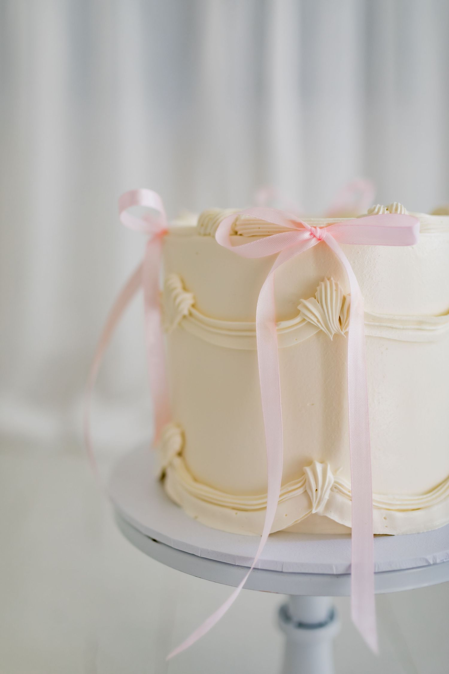 An elegant white wedding cake with pink ribbons and delicate details.