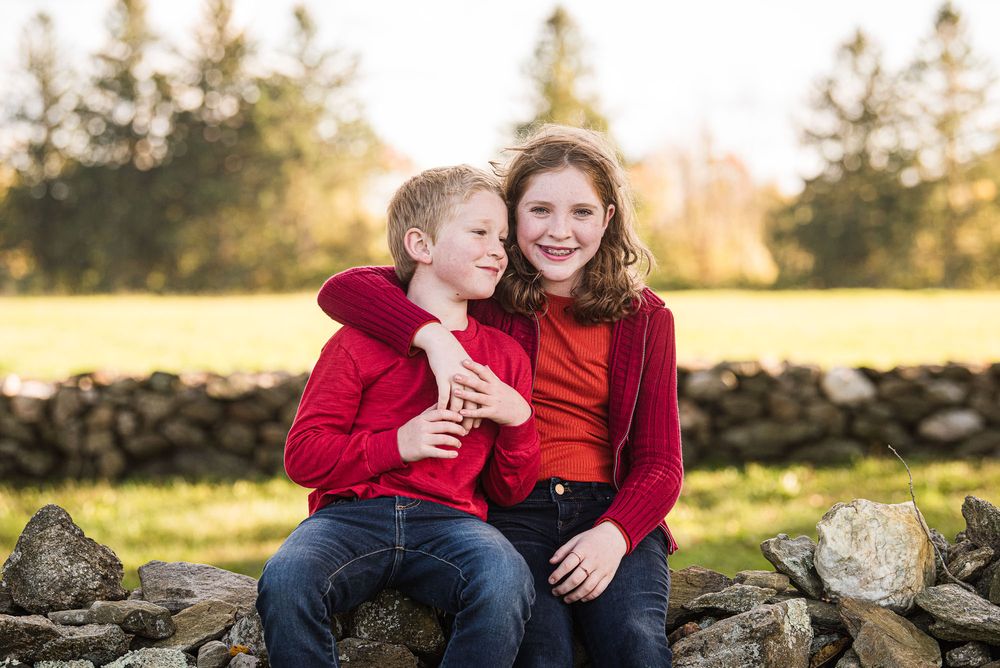 Siblings laughing together with arms around shoulders