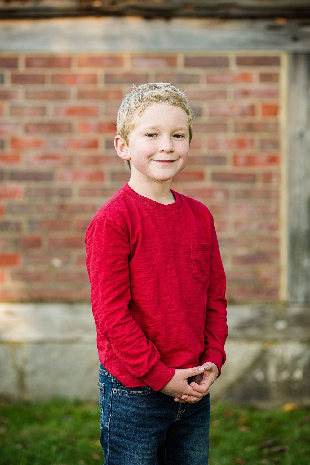Boy smiling with brick wall behind him