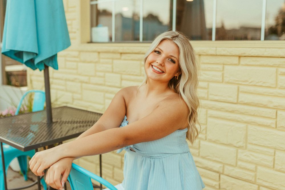 A sunny outdoor portrait against a light stone wall with blue patio decor.
