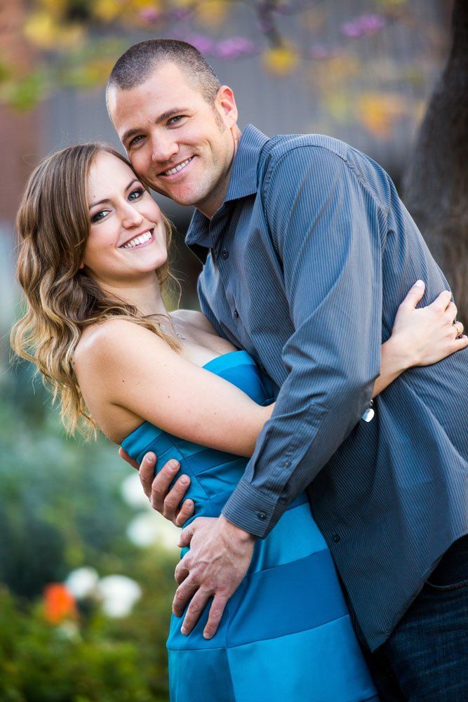 Couple embracing outdoors with autumn foliage in the background.