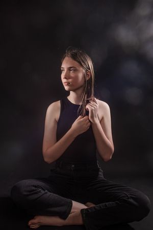 A person wearing black performs a series of graceful dance poses against a dark background.