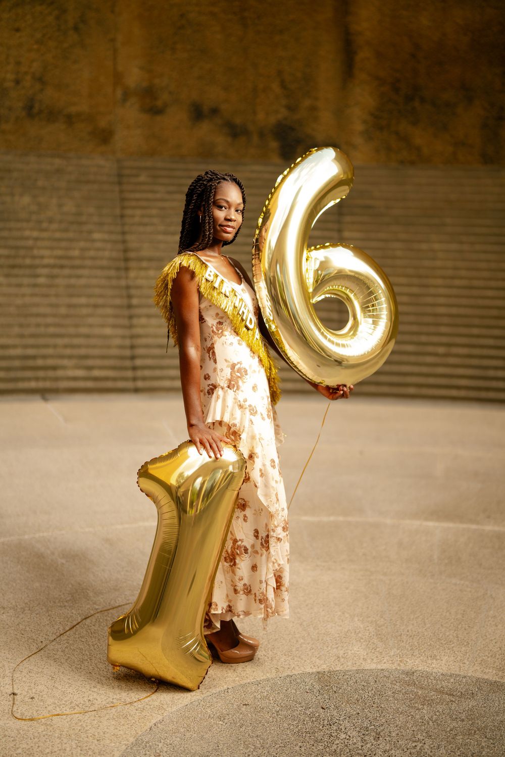 A celebratory scene with gold number 16 balloons and a floral dress for what appears to be a birthday or special occasion.