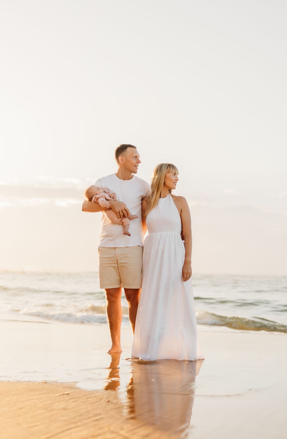 A family photography portrait taken at sunrise in Sunshine coast, Queensland, a family holding a baby in front of the ocean.