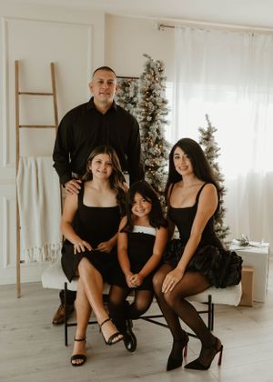 Family dressed in black attire poses elegantly in bright modern studio setting.
