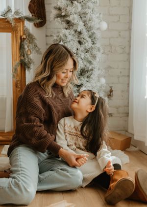 Intimate family moments captured on hardwood floor with holiday decorations in background.
