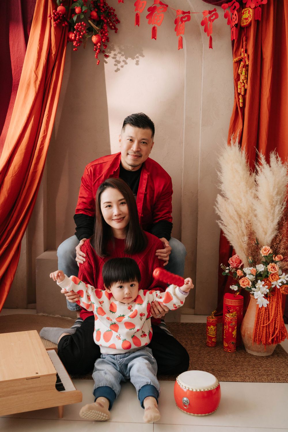 Family portrait with festive red decor, Chinese New Year lanterns and pampas grass arrangements.