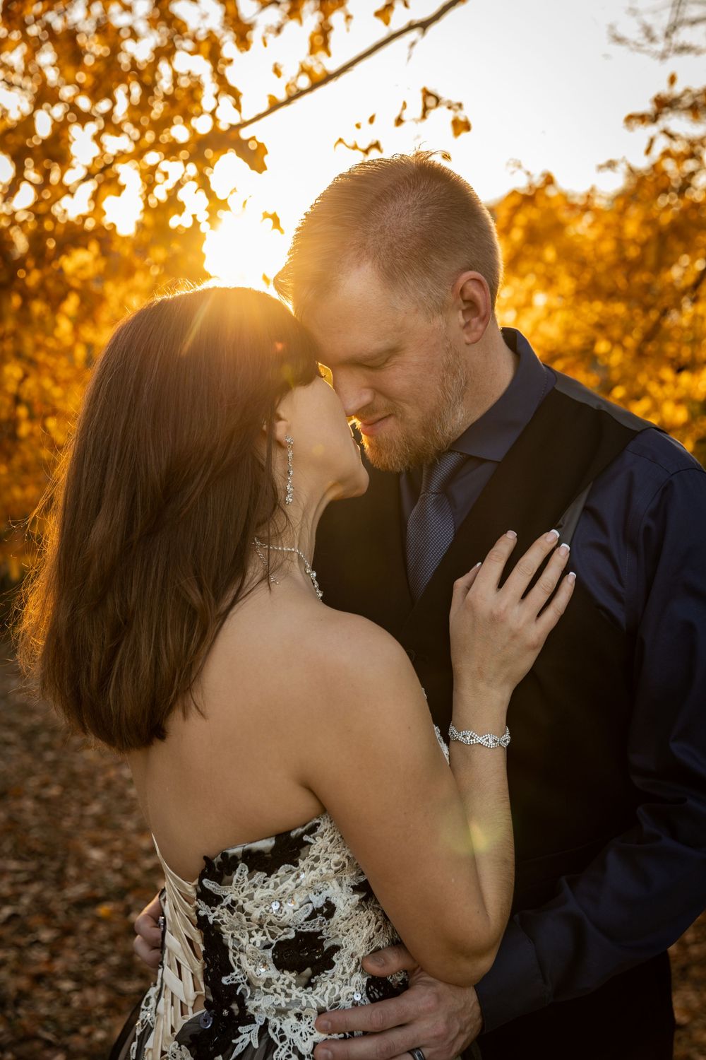 An intimate moment between a couple during sunset with autumn foliage creating a warm backdrop.