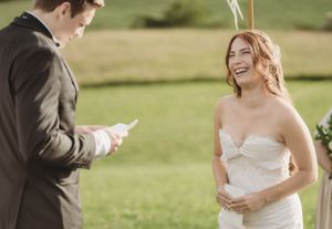 Candid moments between wedding couple during outdoor ceremony in sunlit field.