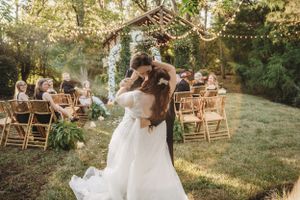 Outdoor wedding reception area decorated with string lights and wooden chairs.