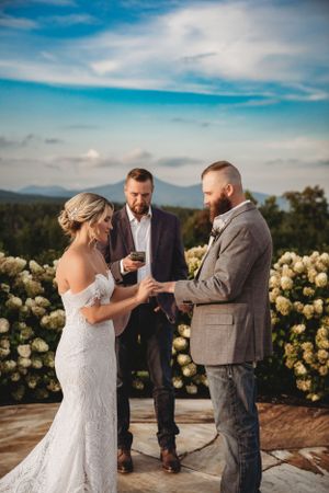 Wedding ceremony on stone patio with mountain views and yellow rose bushes in background.