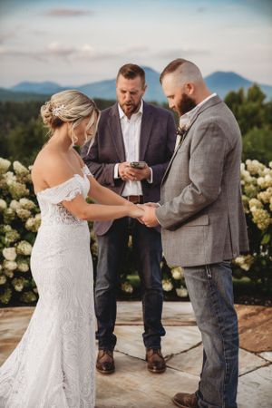 Intimate wedding ceremony moment on stone patio surrounded by blooming yellow roses.