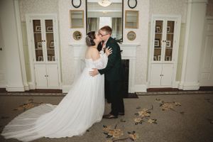 Wedding couple dances in elegant indoor venue with white walls and hardwood floors.