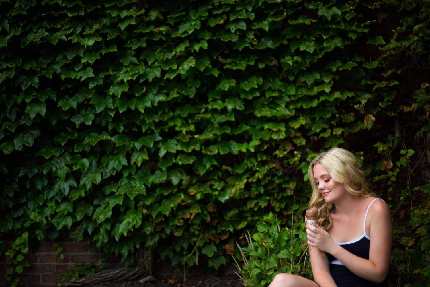 Portrait against ivy wall showing contemplative moment in natural lighting.