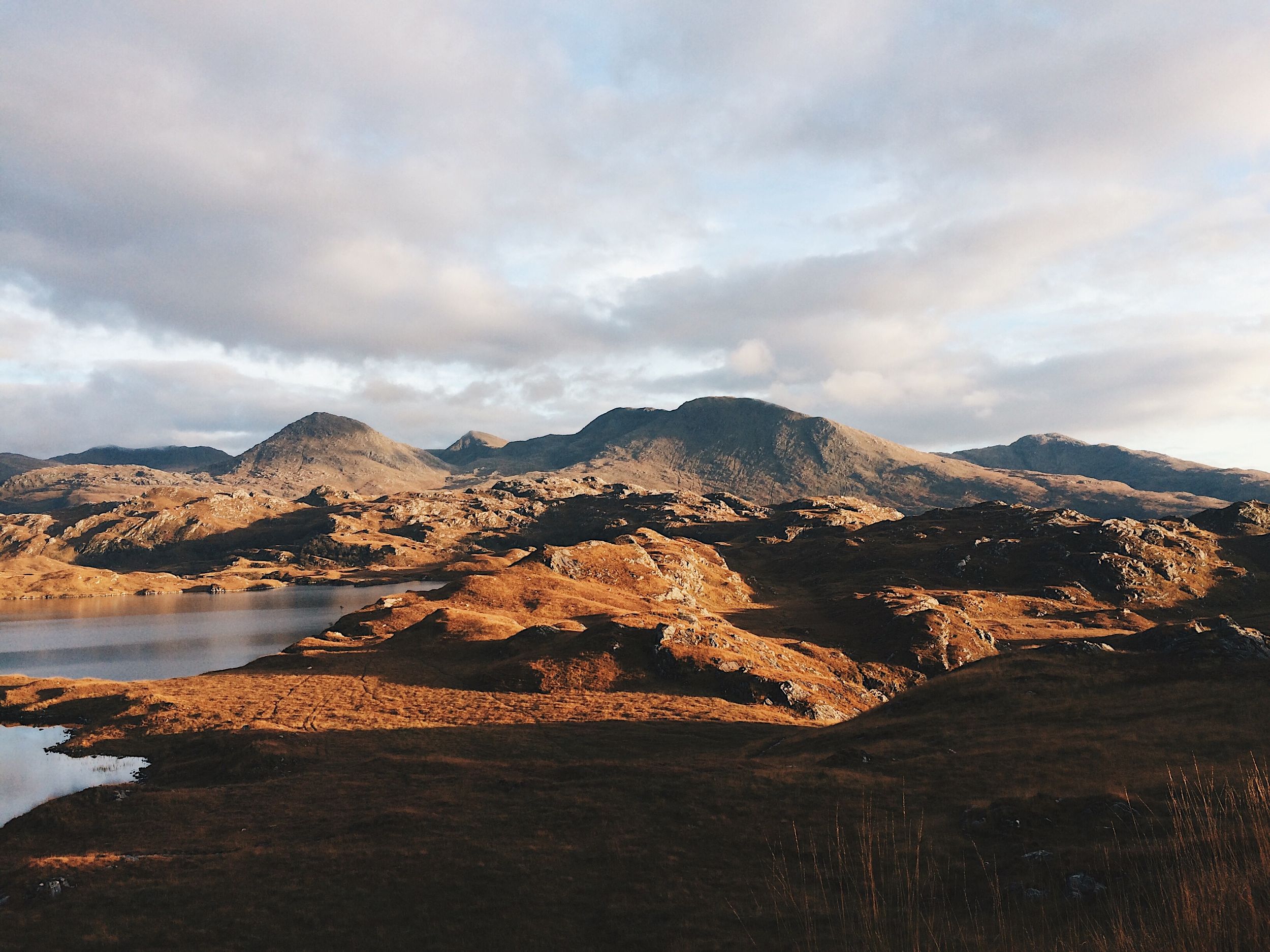 Panoramic view of rugged mountains at sunset with golden light illuminating the peaks.