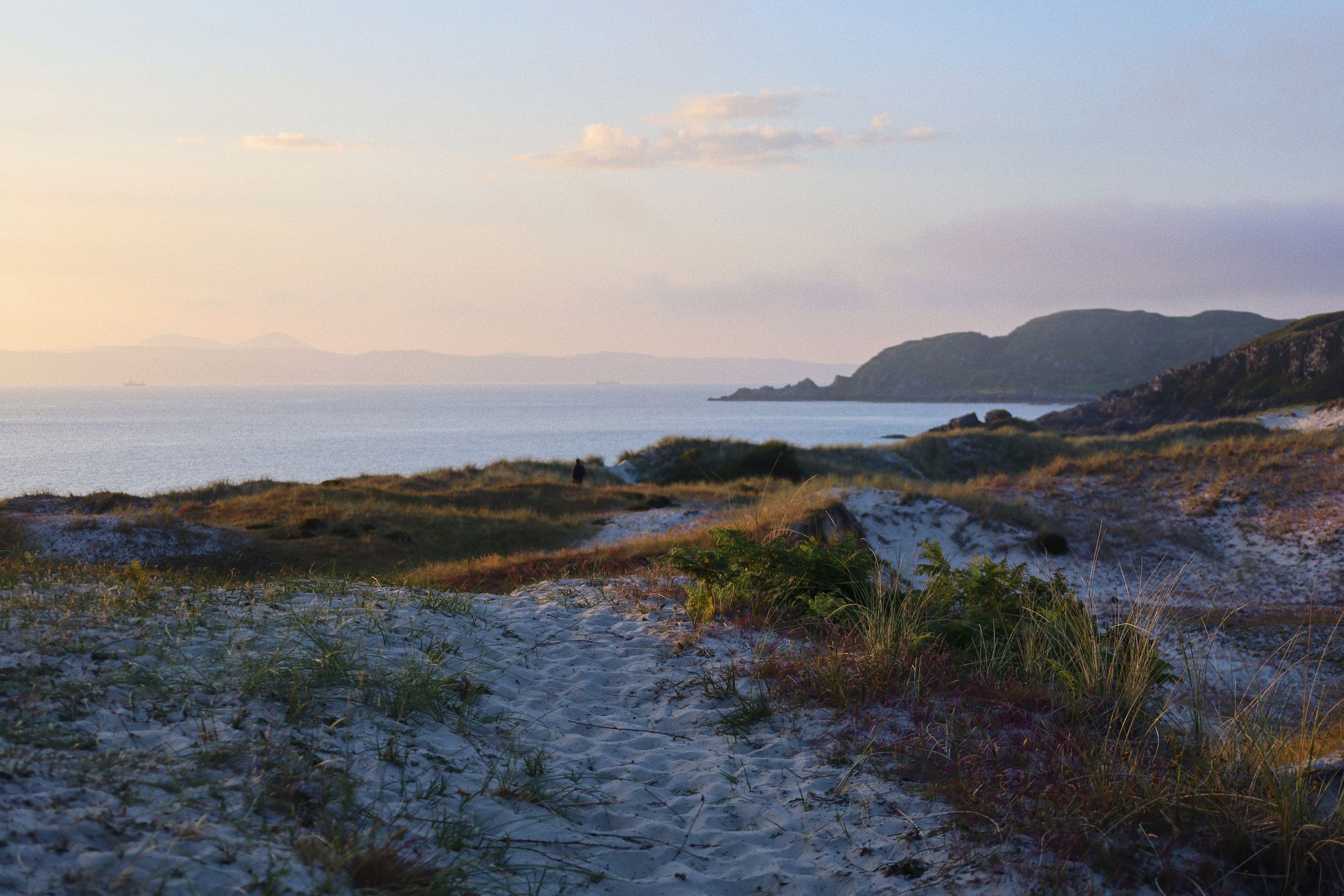 Sunset panorama of a coastal landscape with rocky terrain and distant ocean views.