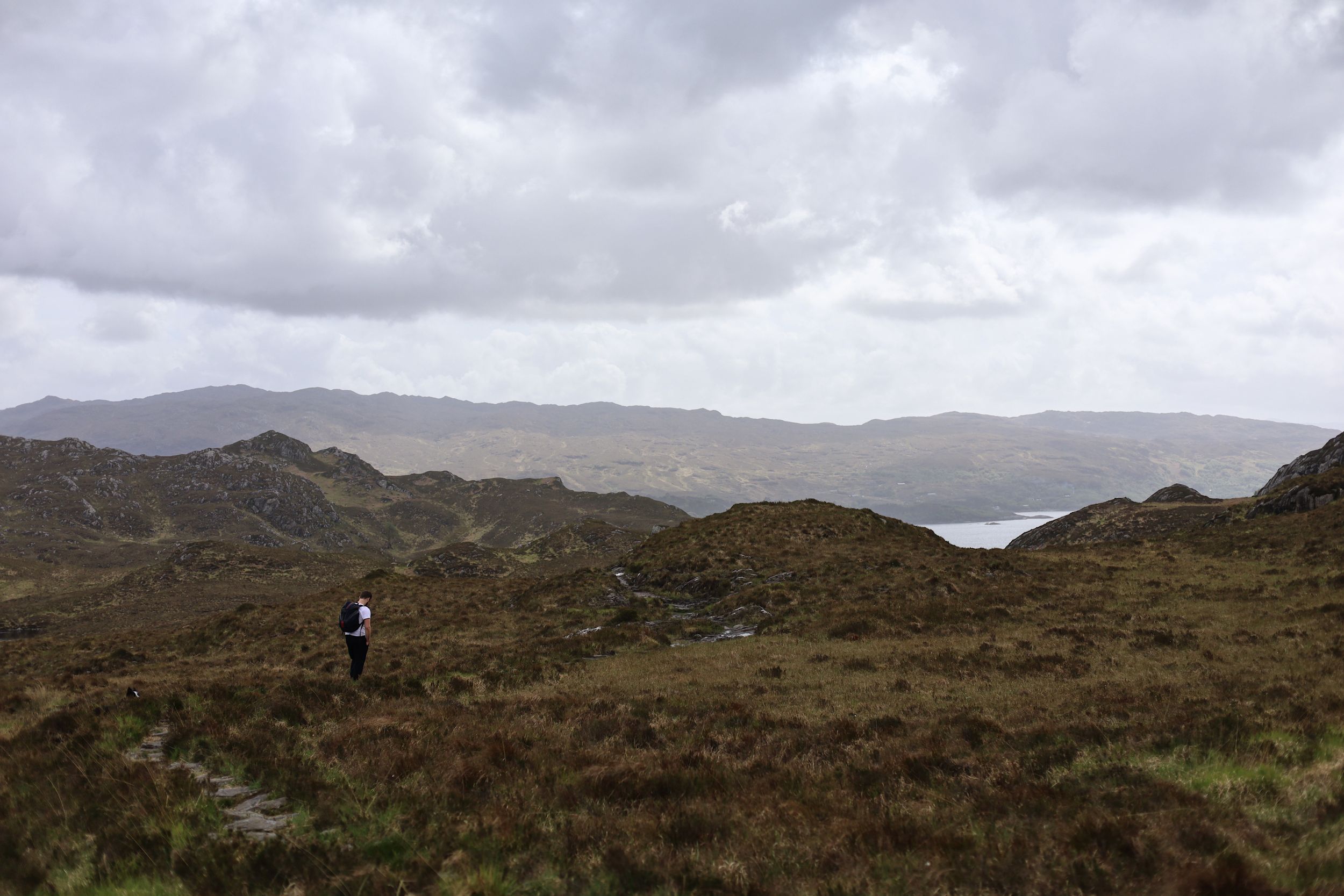 Rugged highland landscape with rolling hills and cloudy skies.