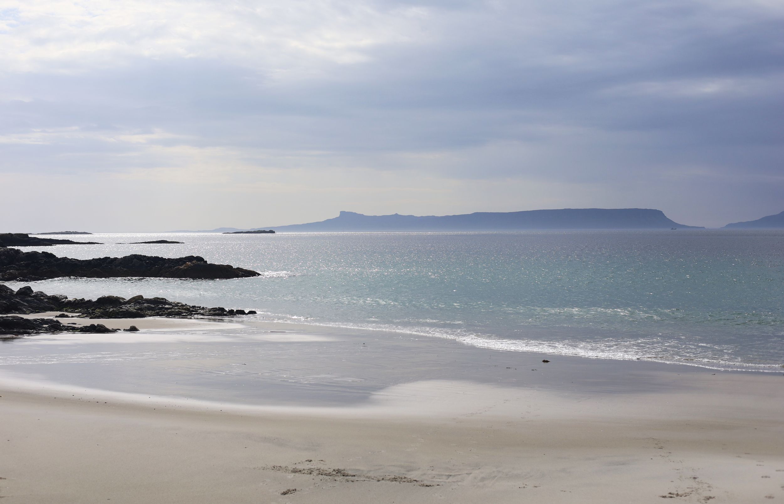 Dramatic coastal landscape with rocky shoreline and misty ocean views stretching to the horizon.