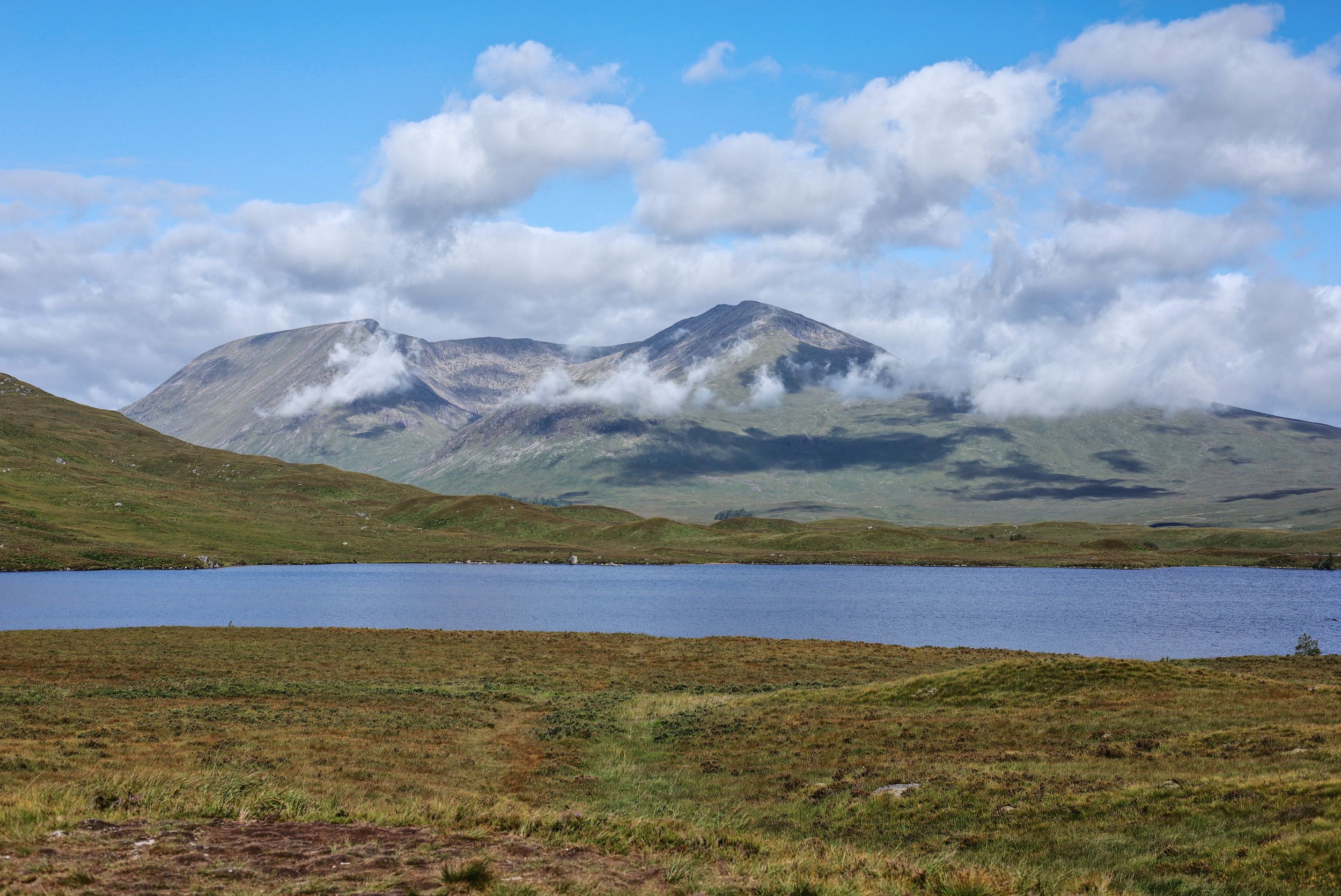 Expansive mountain landscape with rolling hills and cloudy skies across vast moorland terrain.