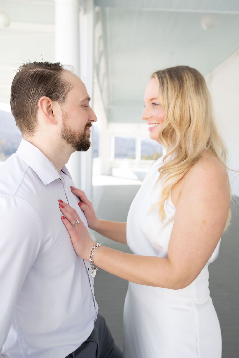 A couple shares playful moments in a bright indoor setting with white walls.