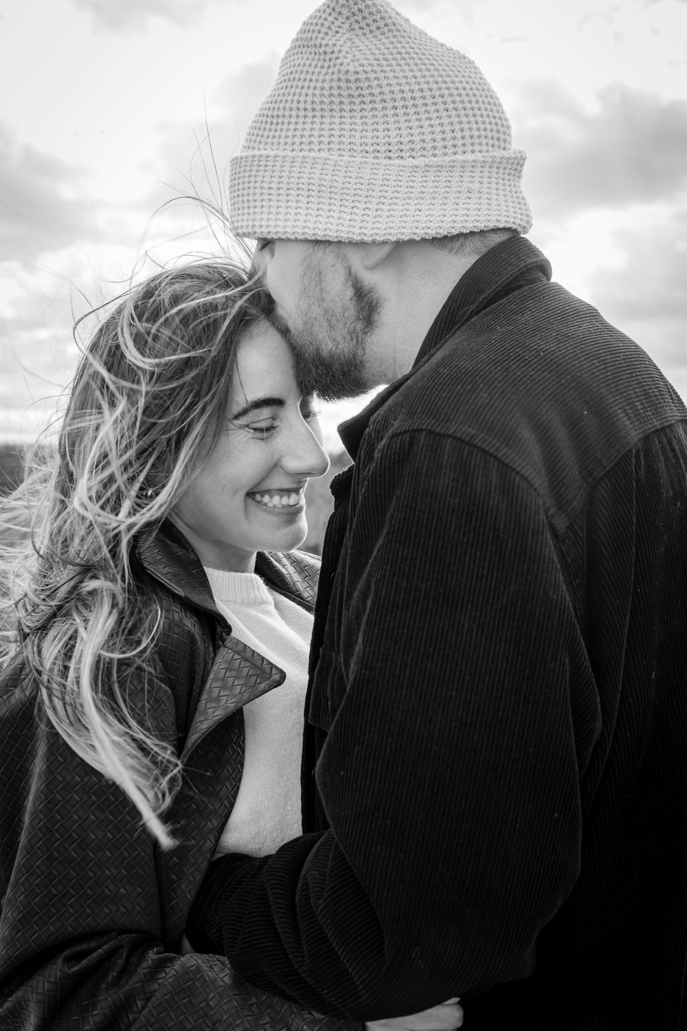 Intimate black and white portrait of couple sharing tender moment outdoors.
