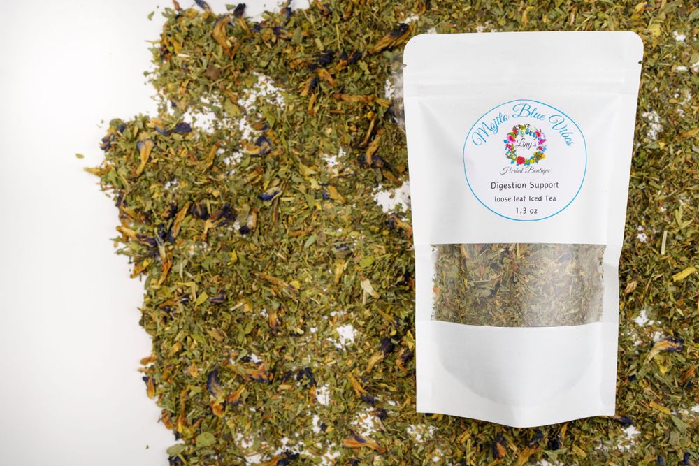 White package of herbal tea blend displayed with scattered dried herbs on white background.