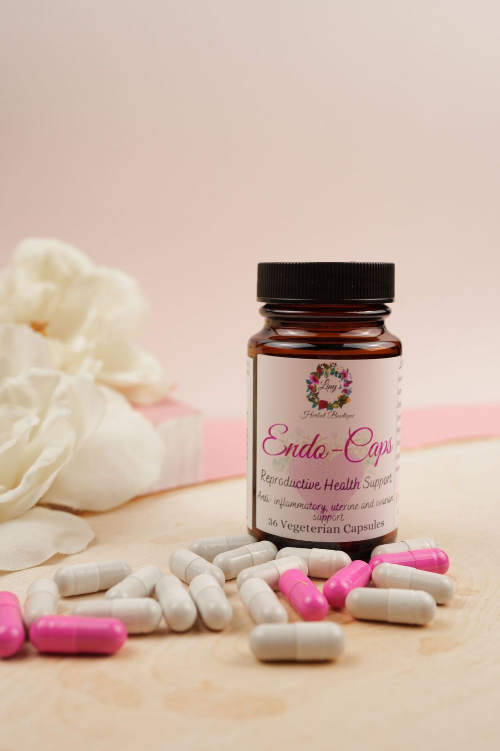 Natural supplement bottle with capsules and white fabric on pink background.
