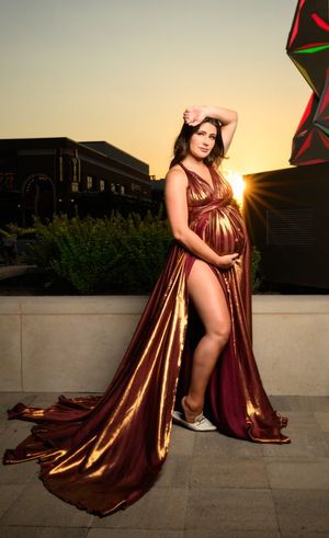 Pregnant woman in gold and burgundy maternity gown posing at sunset outdoors. | Luxury Photography, Maternity Photographer in Cypress TX