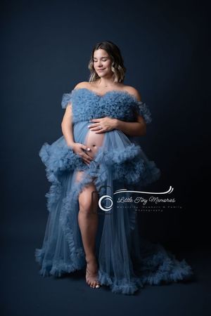 Pregnant woman in blue ruffled tulle maternity gown cradling baby bump during professional studio photography session. Cypress Photographer