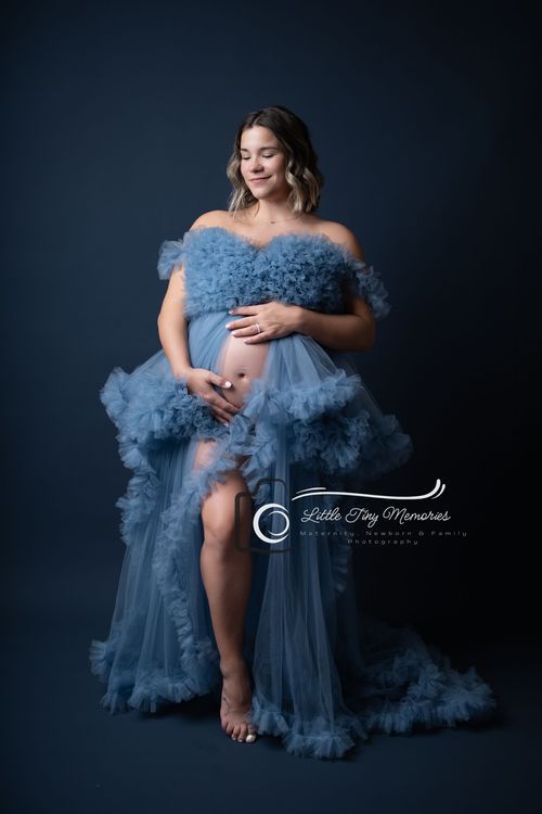 Pregnant woman in blue ruffled tulle maternity gown poses gracefully in professional studio photography session. Cypress Maternity photograp