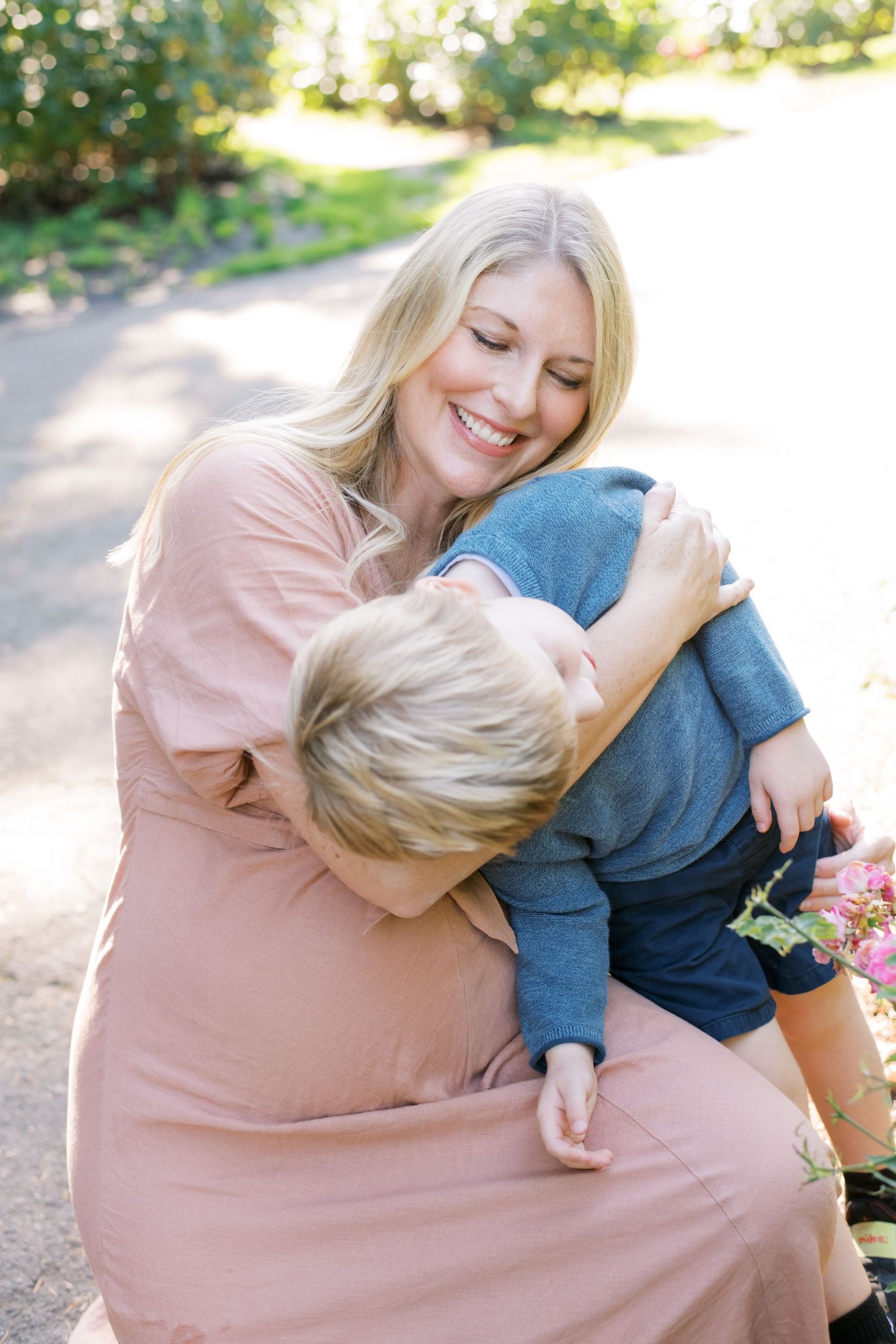 Tender moment between parent and child on sunny outdoor path.