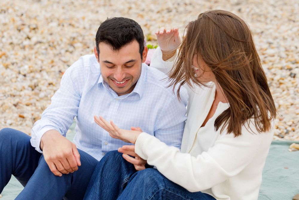 A couple sharing a playful moment while sitting on the beach.