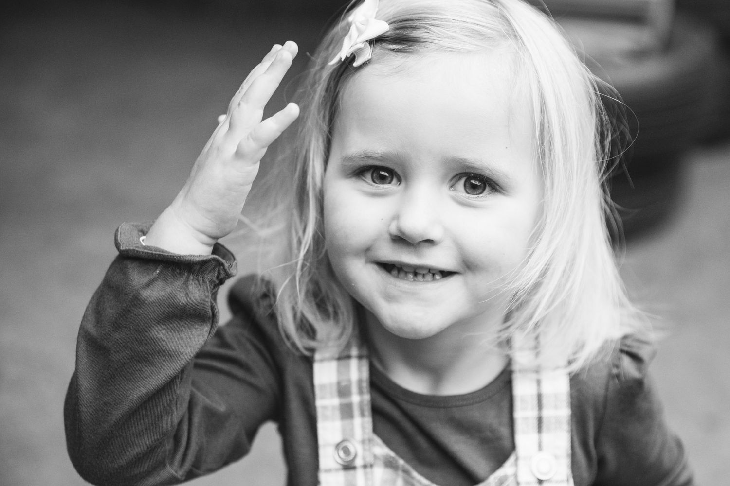 A cheerful black and white portrait with one hand raised in greeting.