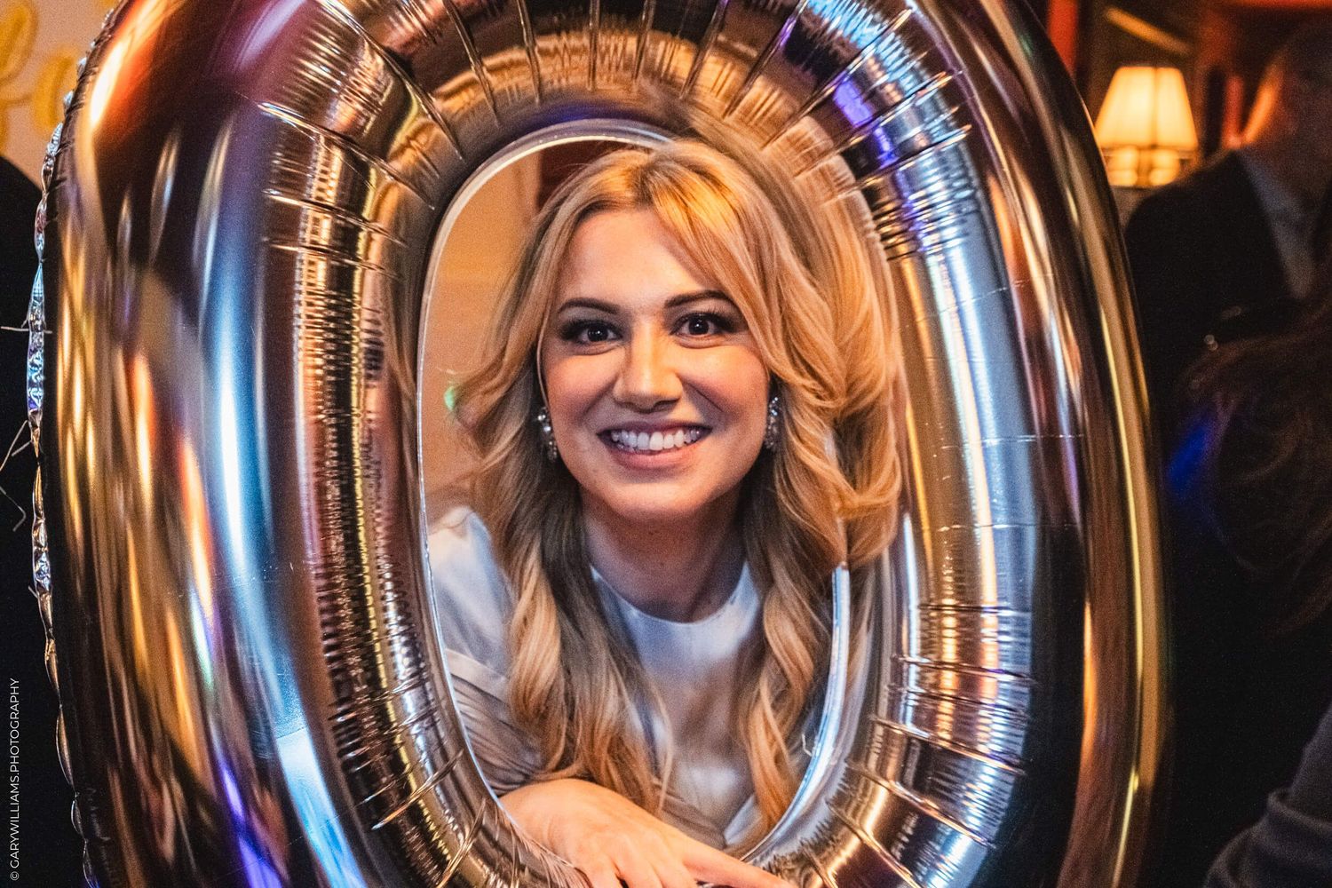 Evie smiling in the opening of a ballon shaped like the number zero.
