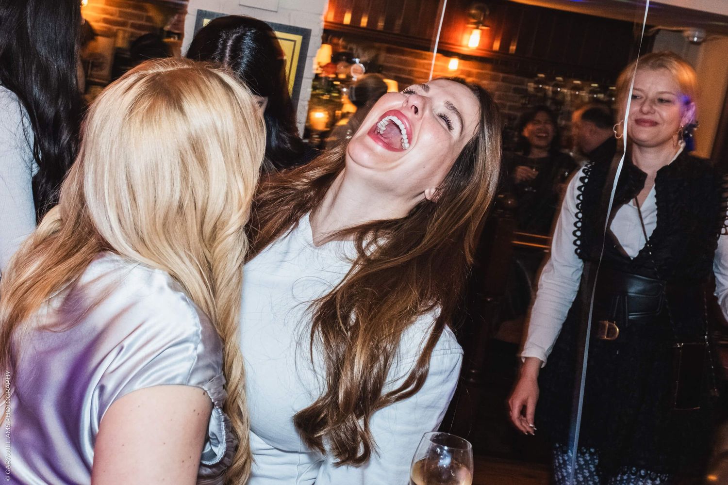A Woman laughing with her friend at a birthday in London.