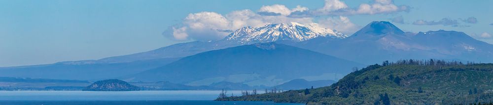 Snow-capped mountains rise above a scenic coastline with multiple bays and inlets stretching into the distance.
