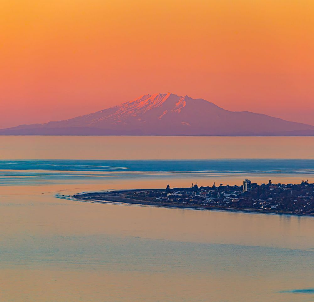 Panoramic sequence showing Mount Rainier at sunset with silhouetted cityscape and calm waters in foreground.