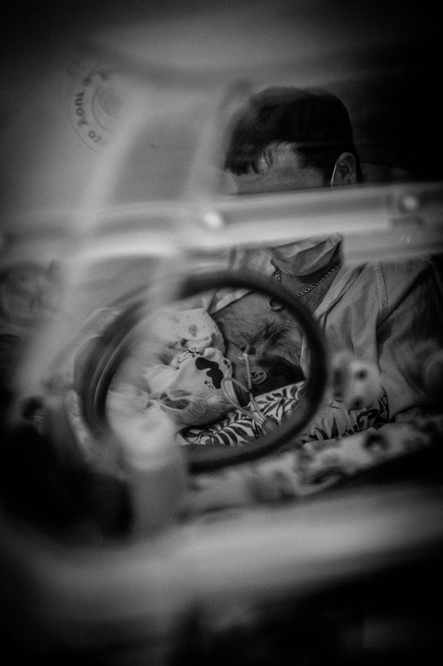 A black and white view through a vehicle mirror showing a peaceful sleeping figure on a bed.