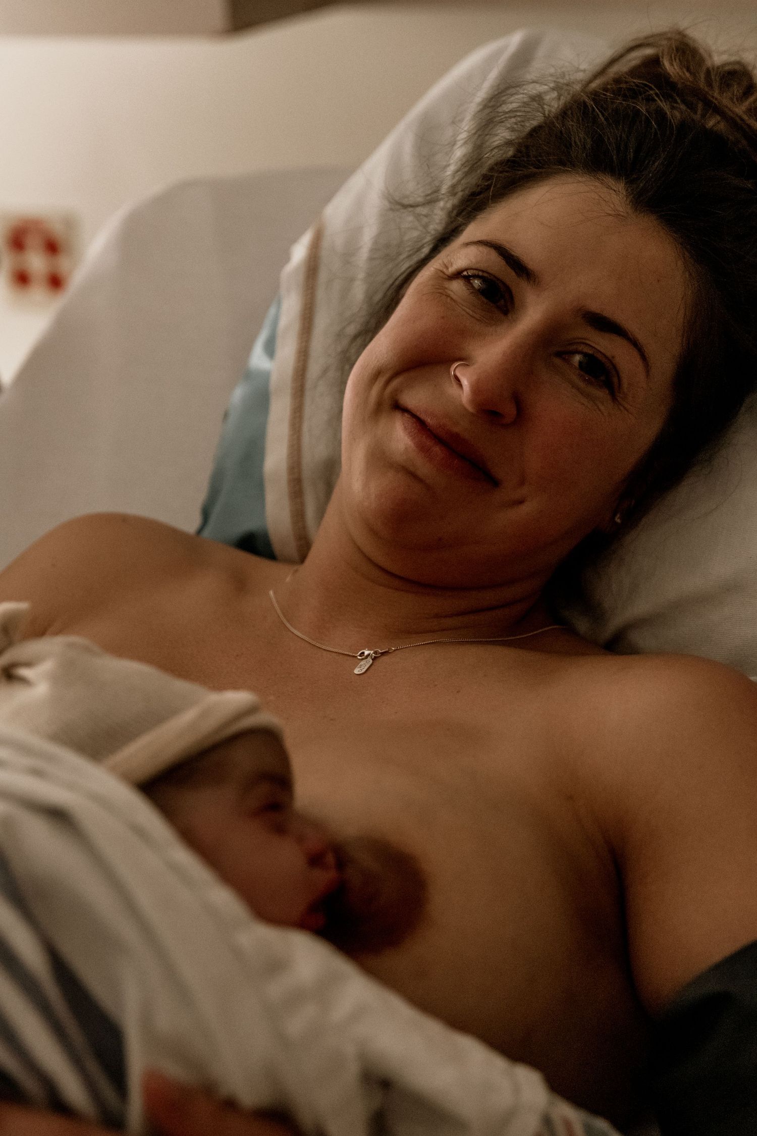 A tender moment captured between a mother and newborn baby during skin-to-skin contact in a hospital bed.