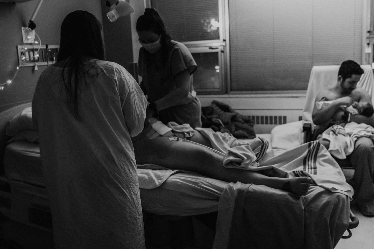 Medical staff attend to a patient in a hospital room in this black and white photograph.