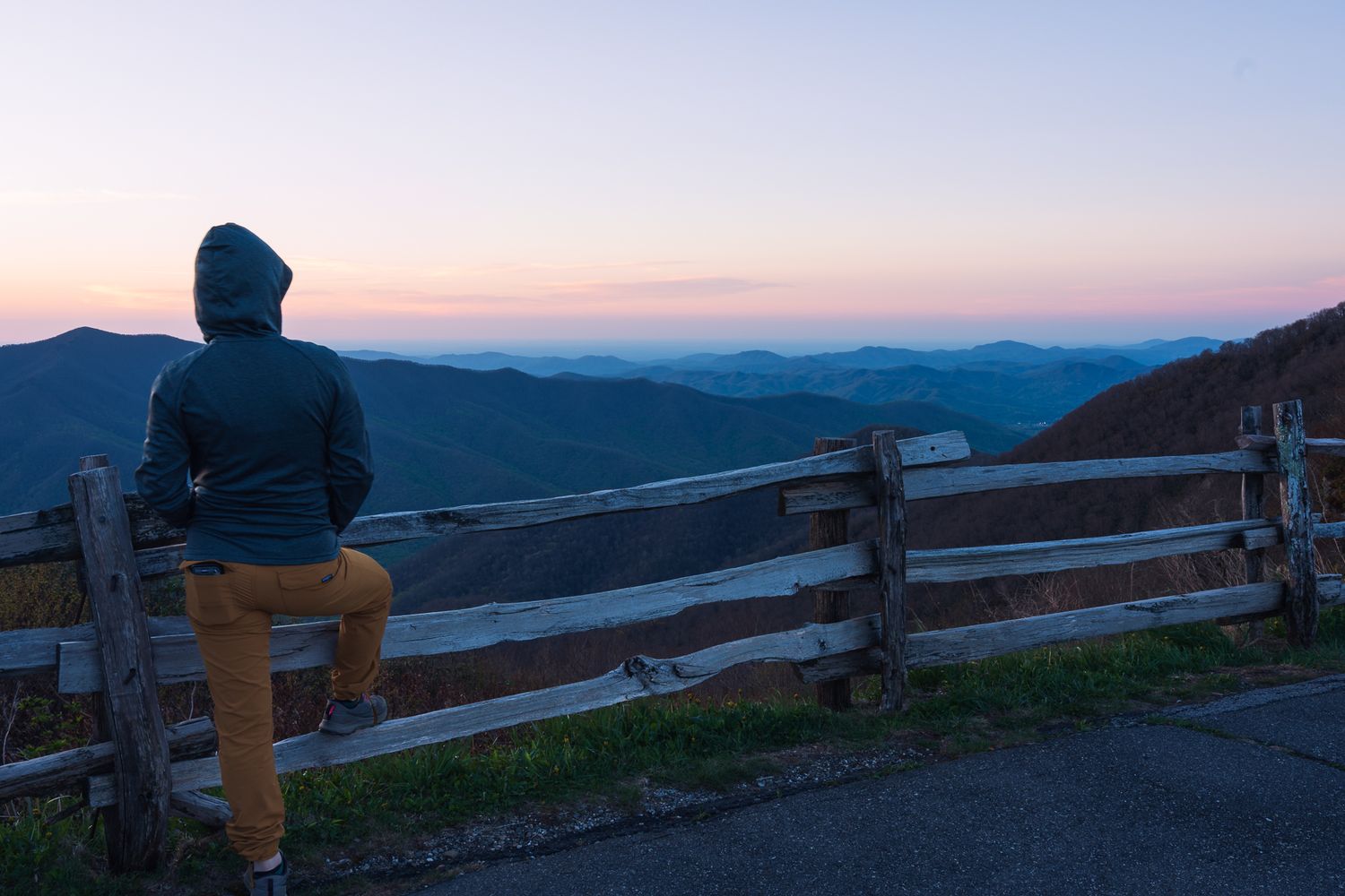 Self portrait of the photographer standing on Tennant mountain with soft clouds, mountains and a pastel sky in the background.